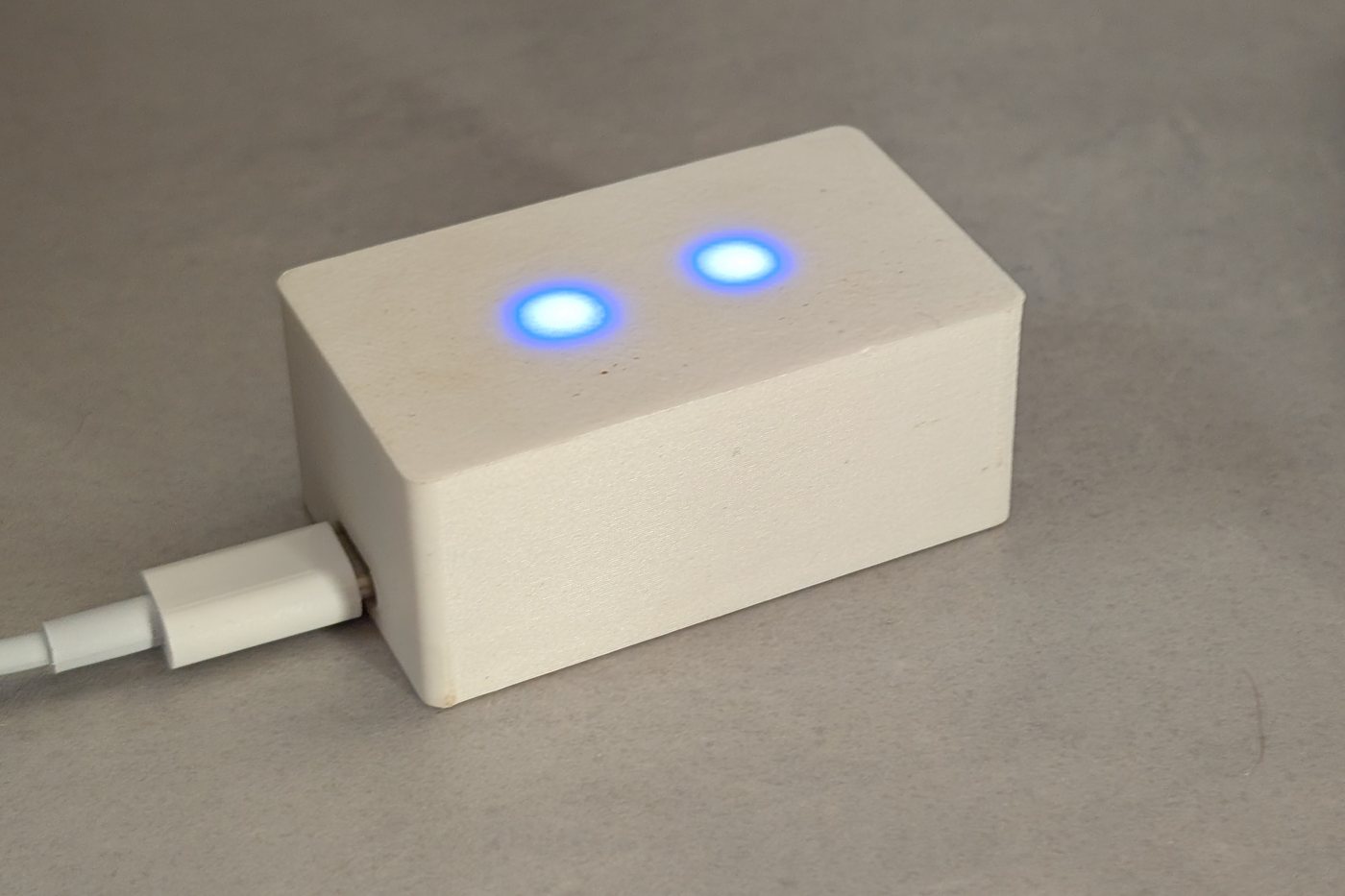 Le boîtier Tempo posé sur un bureau : coffret blanc imprimé en 3D, deux petites lumières bleues allumées.