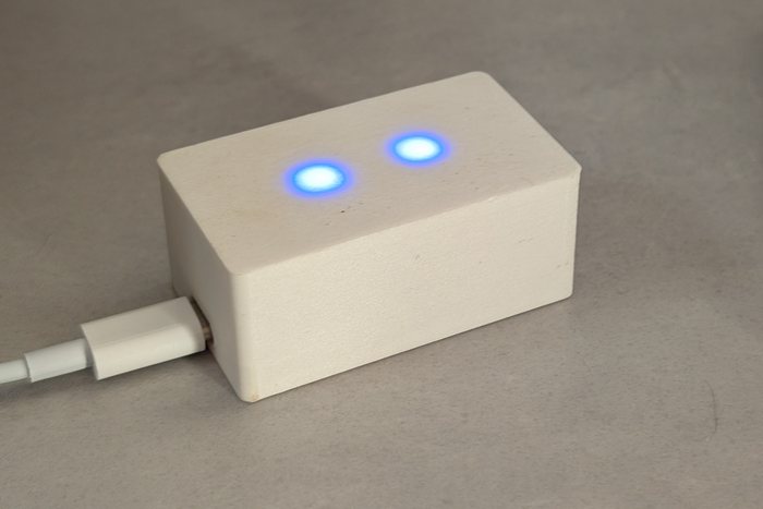 Le boîtier Tempo posé sur un bureau : coffret blanc imprimé en 3D, deux petites lumières bleues allumées.