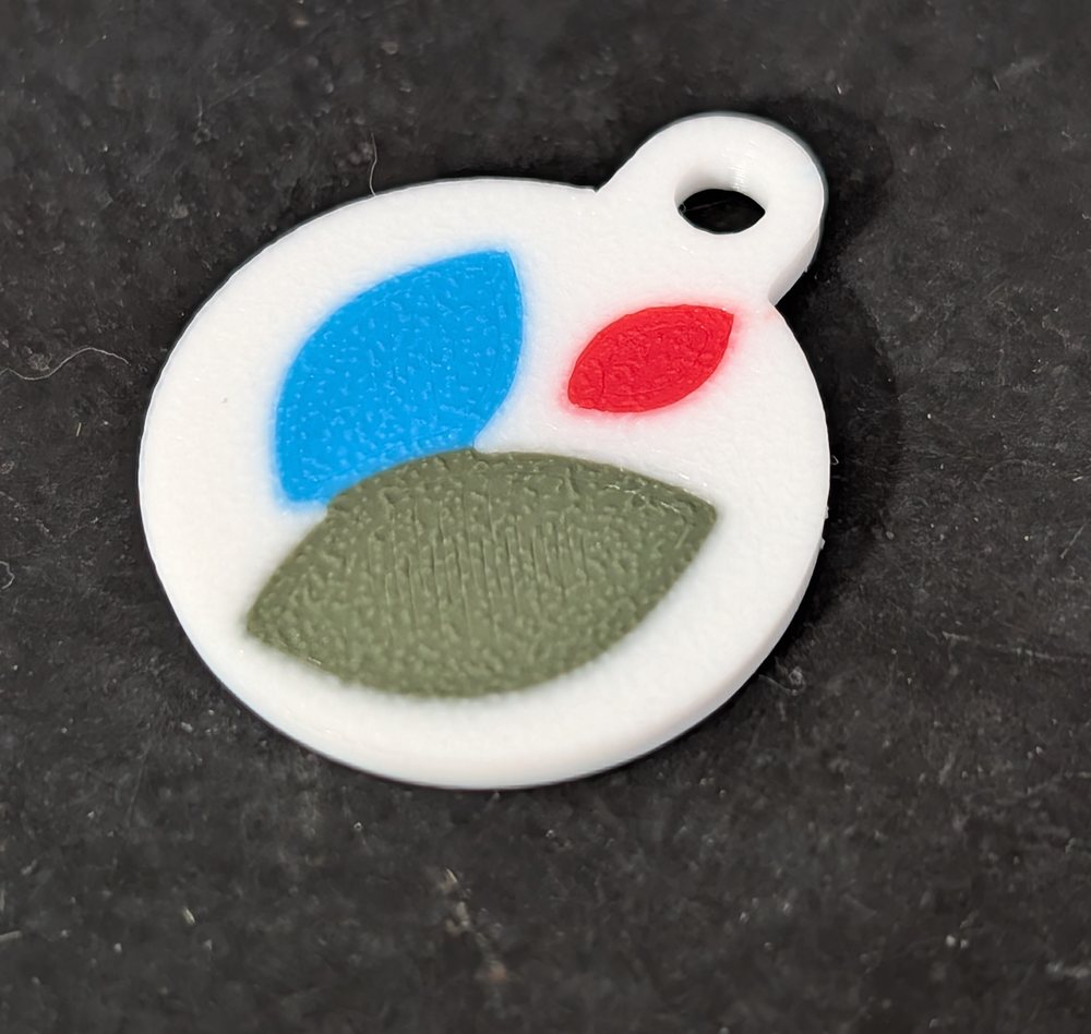 Jeton de caddie blanc imprimé en 3D, percé d'un anneau, orné d'un motif à trois pétales bleu, rouge et vert aux couleurs d'un lycée.